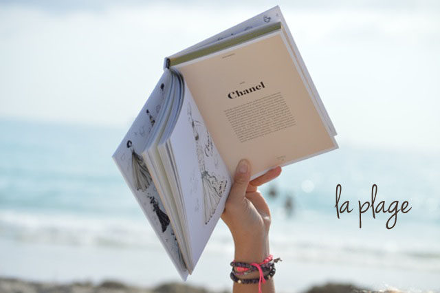 a girl reading a book on the beach pictured id thee open book in the girl's hand with ocean in the background